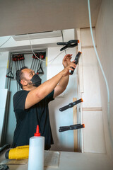 Man using clamps to hold workpiece gluing. DIY project at home.