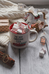 A mug with marshmallows, a white sweater, toys on a light photo background.