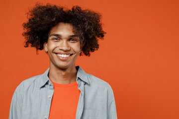 Young smiling happy cheerful satisfied friendly positive black student man 50s wear blue shirt t-shirt look camera isolated on plain orange color background studio portrait. People lifestyle concept.
