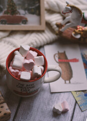 A mug with marshmallows, a white sweater, toys on a light photo background.