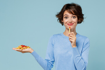 Young happy cool woman wearing casual sweater looking camera hold in palm hand fastfood french...