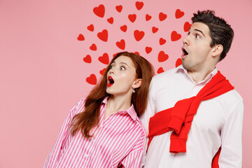 Young surprised shocked couple two friends woman man in casual shirt look aside on workspace area isolated on plain pink background studio portrait. Valentine's Day birthday holiday party concept