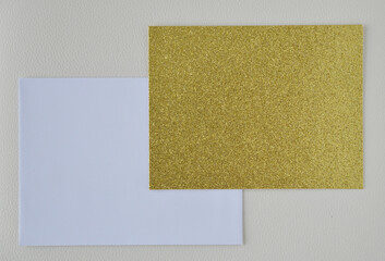 Golden metallic card and white envelop in cream leather background