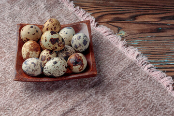 Top view of Quail eggs in wooden plate on wooden background. Selective focus. With copy space.