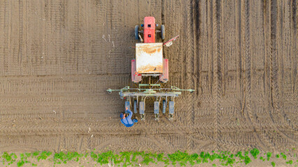 Aerial top shot on farmer as his control amount of seed in sowing machine in agricultural cornfield
