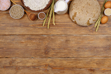 Homemade bread and ingredients for baking on dark rustic wooden background