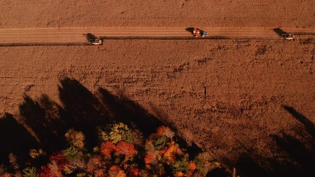 4K AERIAL FOOTAGE OF COMBINE OPERATION WITH SUPPORTING TRACTORS REAPING WEATH IN QUEBEC CANADA