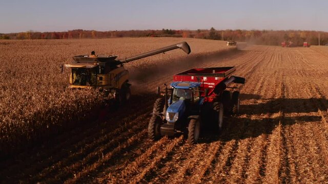 4K AERIAL FOOTAGE OF COMBINE OPERATION WITH SUPPORTING TRACTORS REAPING WEATH IN QUEBEC CANADA