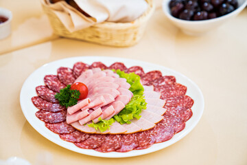 round white plate with chopped sausage, meat, lettuce, herbs and tomato. snack for the festive table. meat products store.