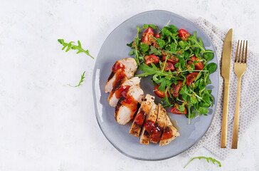 Roasted chicken fillet with salad  fresh tomatoes and arugula. Top view, flat lay