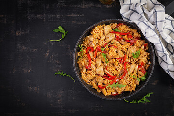 Heart-shaped pasta  in tomato sauce with chicken and sweet pepper with arugula on a dark table. Top view