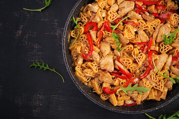 Heart-shaped pasta  in tomato sauce with chicken and sweet pepper with arugula on a dark table. Top view