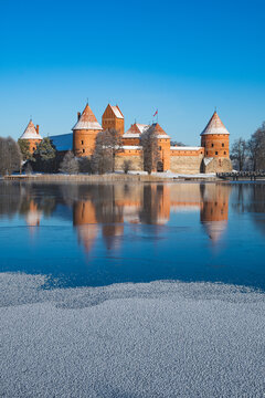 Medieval castle of Trakai, Vilnius, Lithuania, Eastern Europe, located between beautiful lakes and nature with beautiful sky and blue lake in winter with snow, frozen lake and blue sky, vertical