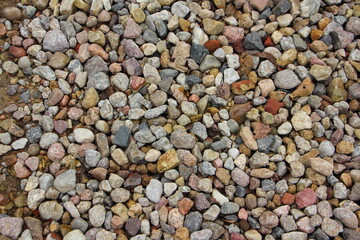 Small colored dry stones on the sand background texture