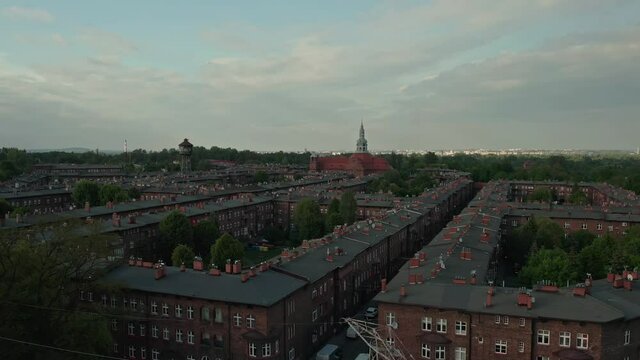 Aerial View Of Red Brick Apartments In Nikiszowiec, Katowice, Poland With St. Anne Parish Church In Distance. ascending shot