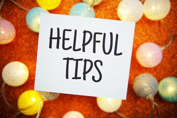 Helpful Tips text on paper card with LED cotton balls decoration on orange background