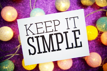 Keep It Simple text on paper card with LED cotton balls decoration on purple background