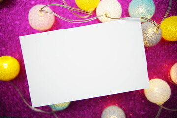Empty paper card mockup and LED cotton balls decoration on pink bokeh background