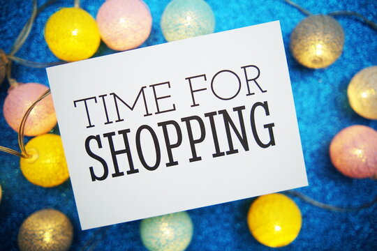 Time for Shopping text on paper card with LED cotton balls decoration on blue background - Powered by Adobe