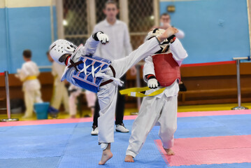 Fototapeta na wymiar Kids fighting on stage during Taekwondo tournament. Blurred background