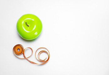 Healthy and healthy snack: green apple and measuring tape, diet and sports on a white background with space for text. The concept of a healthy lifestyle, top view