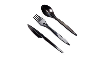 A set of plastic cutlery knife, fork and spoon in black, filmed on a white background