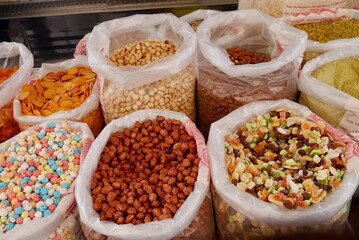 Assortment of nuts and dried fruits in bags at market stand in Sicily, Italy.
