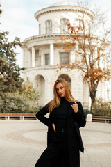 A young beautiful woman in a black coat walks around the city