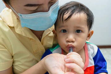 asian woman mother gives some medicine to a little baby. Healthcare and medicine concept.