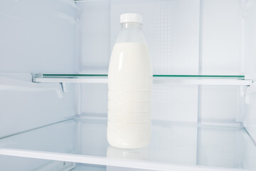 a bottle of milk on a shelf in an empty refrigerator