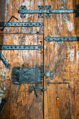 Medieval wooden door with grunge lock and hinges made of wrought iron