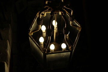 Electric candles lit up in a glass chandelier with a black background (scotland)
