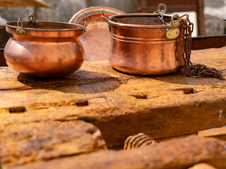 Close-up of vintage copper cauldrons on antique carpenter workbench