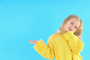 Cute little girl in sweater on blue background