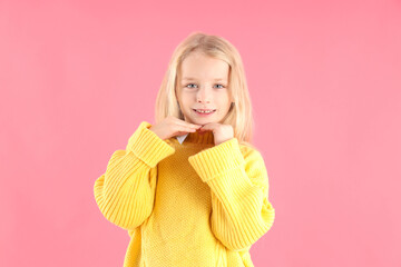 Cute little girl in sweater on pink background