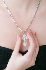 Trendy silver cross and chain on a beautiful young girl. Beauty and fashion 
