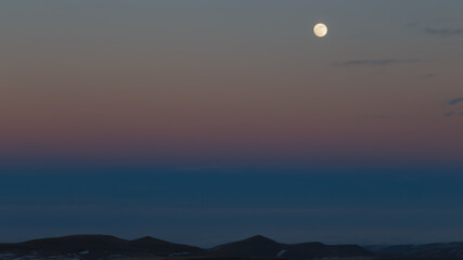The moon in the setting cloudy winter sky