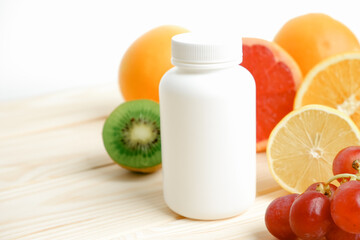 Supplements or natural food? White empty bottle for vitamins on a wooden table. Juicy ripe citrus fruit slices. lemon. Orange. Grapefruit. Grape.