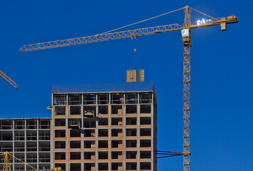 Kyiv, Ukraine -  On the top floor of the new building under construction, large-sized structures are installed using a crane. Construction of a modern residential complex. Blue sky.