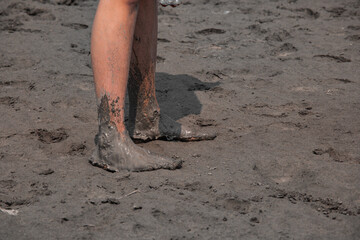 Closeup of the man's muddy feet on the beach.