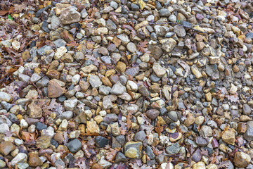 A pile of rough stones mixed with fallen autumn leaves at a construction site