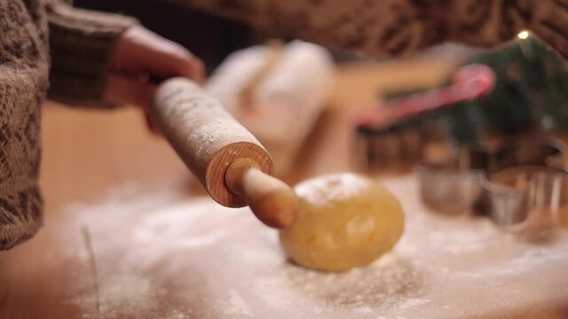 Woman sprinkles flour on rolling pin for making gingerbread. Christmas mood. Side view. Slow motion