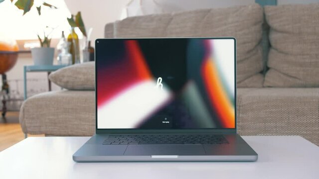 Front view, person's hand lift up M1 MacBook Pro's display. Cozy home background