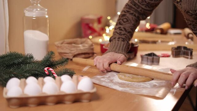 Woman using rolling pin for making gingerbread. Close-up of rolling raw dough for gingerbread. Christmas mood. Preparing for hollidays