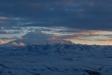 Elbrus in the clouds in the light of the sunset rays