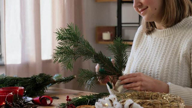 winter holidays, diy and hobby concept - close up of happy smiling woman with fir branches and pruner making christmas wreath at home