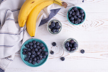 Organic blueberries and bananas at a rustic whitewashed table. Healthy eating concept