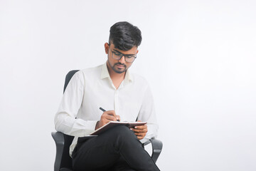 Young Indian male writing some detail in dairy over white background.