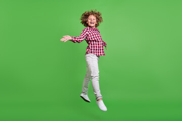 Full length body size view of attractive cheerful guy jumping having fun rest isolated over shine green color background