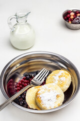 Berries, fork and cottage cheese pancakes and berries in metal bowl.
